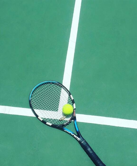 Ein Tennisball auf einem Tennisschläger auf einem Tennisplatz.