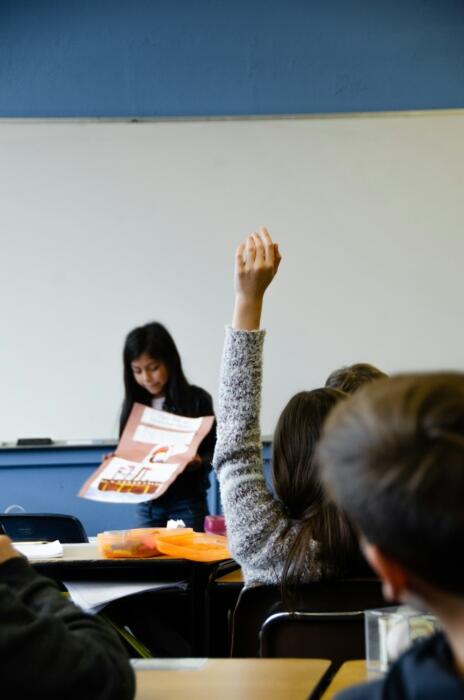 Eine Schülerin zeigt in der Klasse auf.